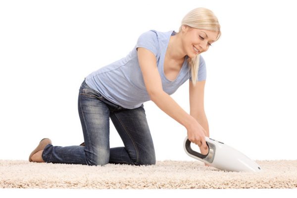 39282218 - young  blond woman cleaning a carpet with a handheld vacuum cleaner isolated on white background